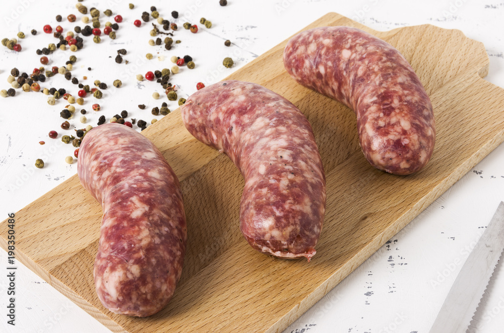 Three sausages on cutting board, on white background. Three sausages on cutting board, on white background.