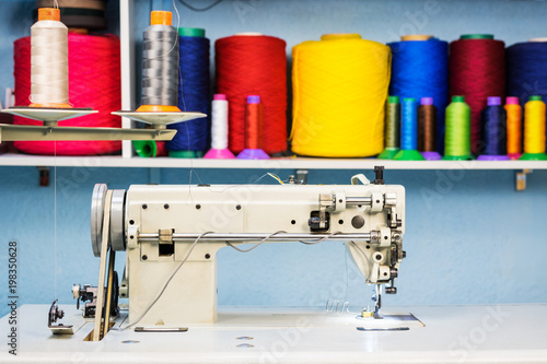 sewing machine overlock in tailor workshop on the background of a shelf with colorful threads photo