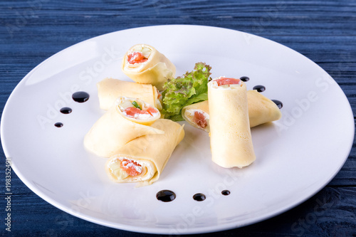 Salmon lavash rolls with cheese and herbs on glass plate, close up view