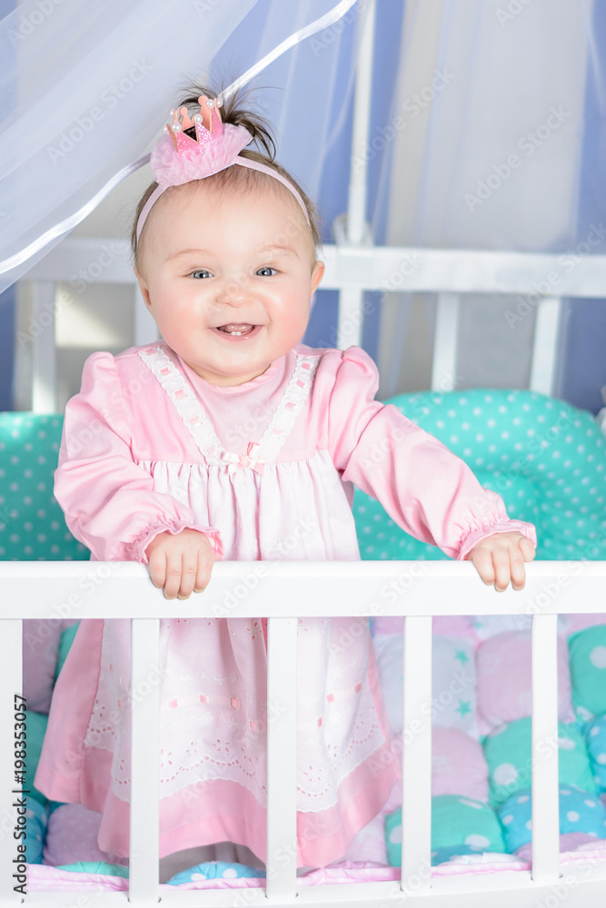 Little beautiful girl in a pink dress laughs in a baby bed Little beautiful girl in a pink dress laughs in a baby bed