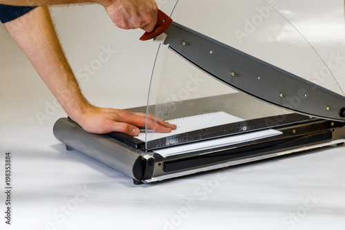 Man using manual paper cutter on white background. Manufacture work. photo