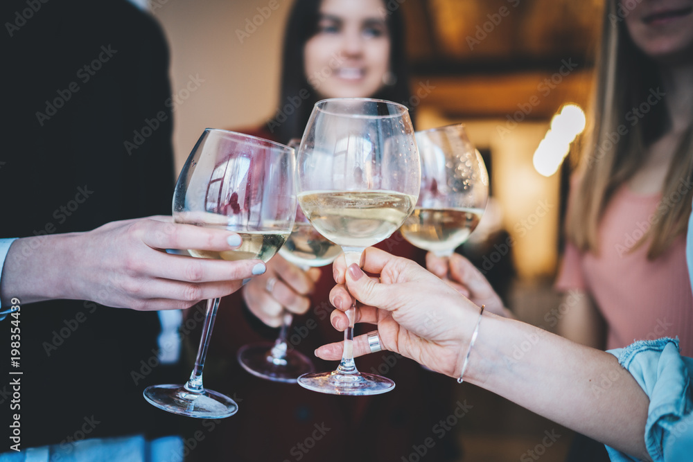 Happy friends cheering with glasses of champagne at home party with healthy food, group of people enjoying and toasting at modern loft, togetherness and friendship concept, filtered image