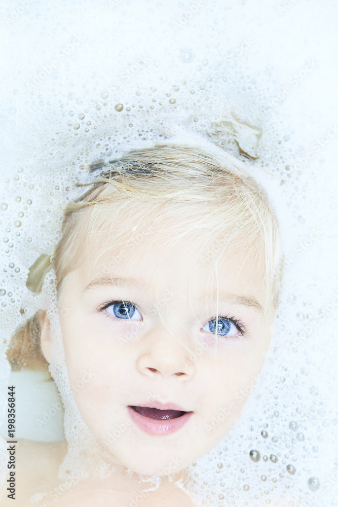 Happy little baby girl face swimming in the bathroomand smile. Portrait of baby bathing in a bath full of foam
Happy little baby girl face swimming in the bathroomand smile. Portrait of baby bathing in a bath full of foam