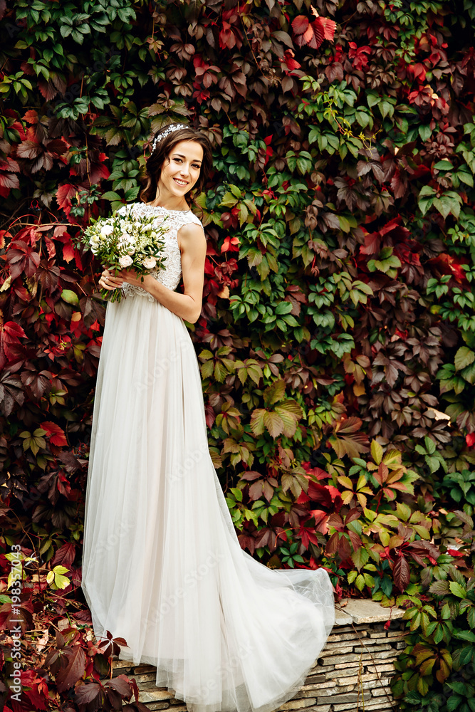  bride posing in front ol old brick wall with ivy