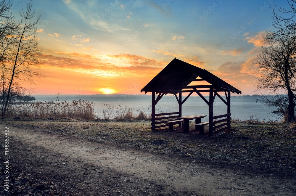 Beautiful morning by the lake. Wooden shed on the shore of a lake at sunrise.