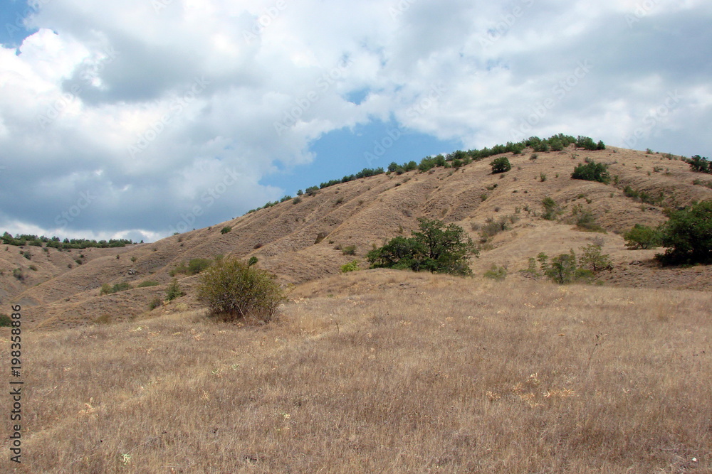 Panorama of the poor nature of the sandy Crimean mountains against the background of the cloudy sky.