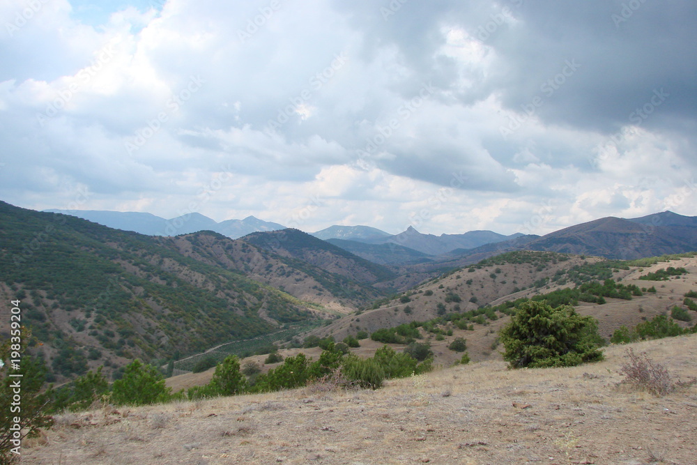  Panorama of a cloudy blue sky over the Crimean mountain ranges on a warm summer day.