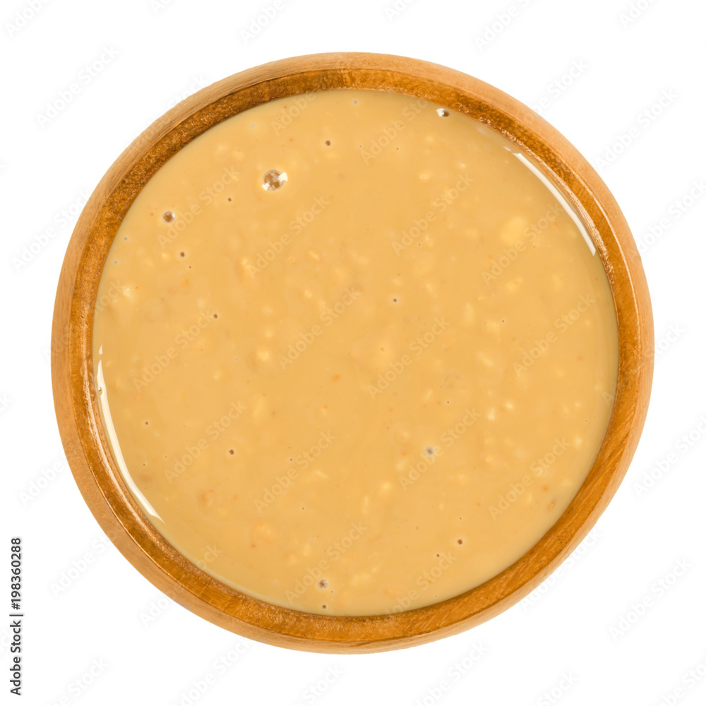Crunchy peanut butter in wooden bowl. Food paste or spread. Made from ground dry roasted peanuts. Arachis hypogaea. Groundnuts or goober. Isolated food photo close up from above on white background. Crunchy peanut butter in wooden bowl. Food paste or spread. Made from ground dry roasted peanuts. Arachis hypogaea. Groundnuts or goober. Isolated food photo close up from above on white background.