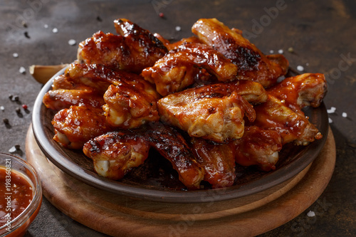 Grilled chicken wings with bbq sauce on the clay plate on the table.