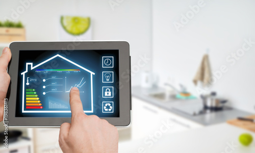smart home and technology concept - close up of male hands pointing finger to tablet pc computer with house settings on screen over kitchen background