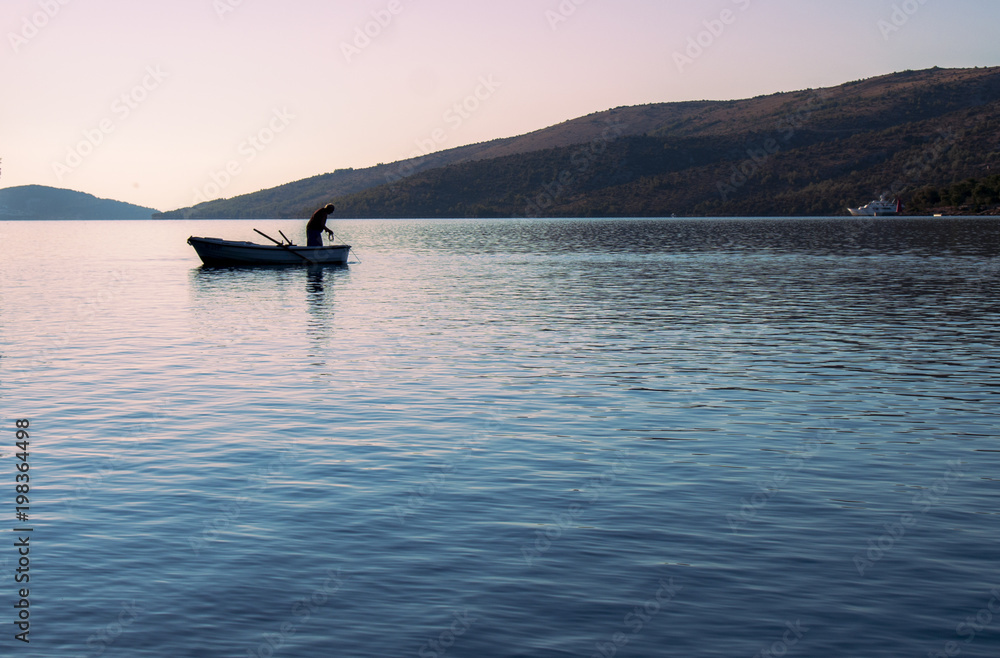 Fototapeta premium The fisherman on the old boat is hunting fish