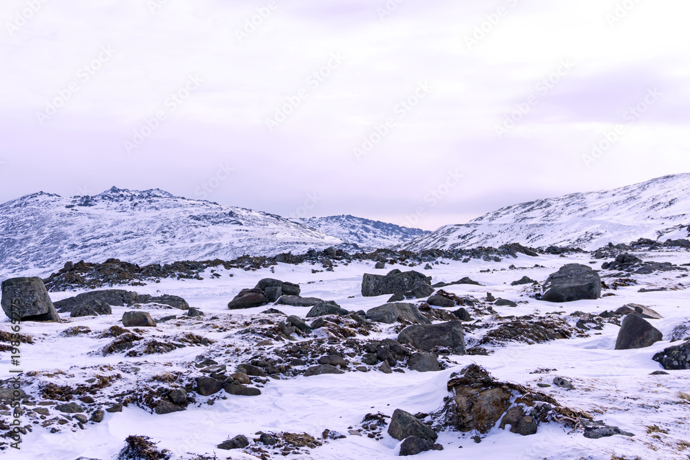 snowy highland plateau with granite boulders in the foreground and mountain peaks in the background