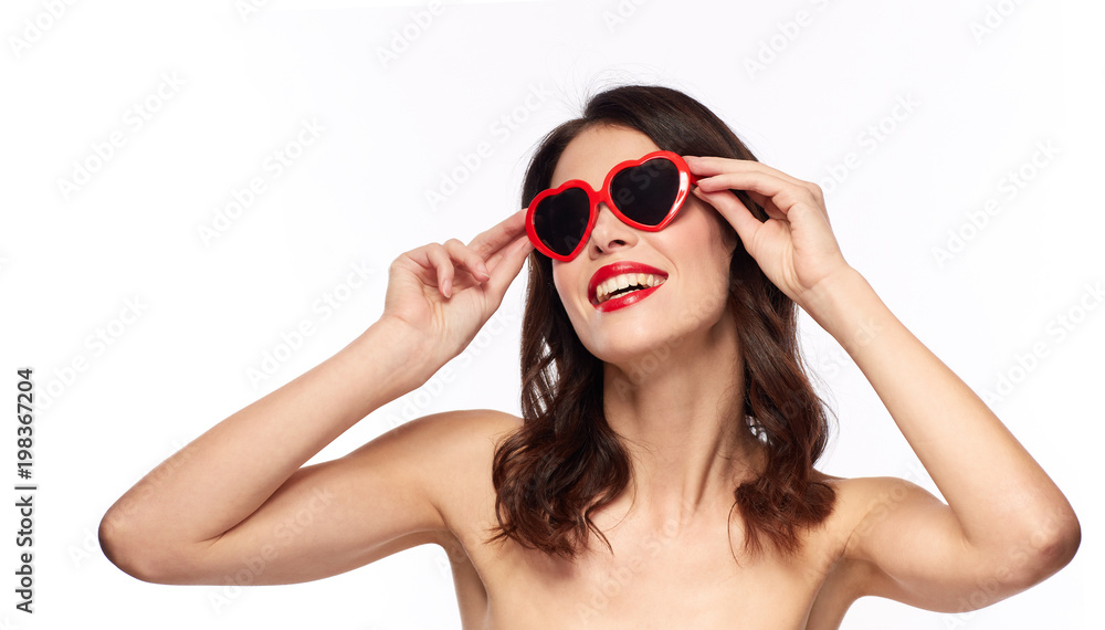 valentines day, beauty and people concept - happy smiling young woman with red lipstick and heart shaped sunglasses over white background valentines day, beauty and people concept - happy smiling young woman with red lipstick and heart shaped sunglasses over white background