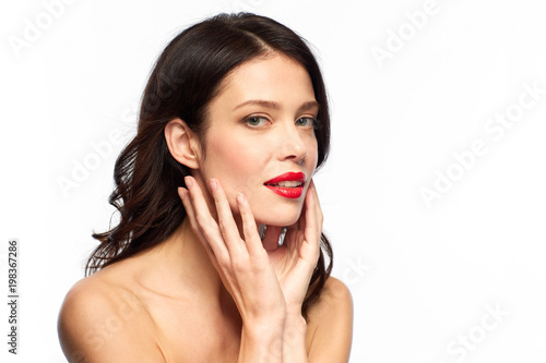 beauty, make up and people concept - happy smiling young woman with red lipstick over white background touching her face