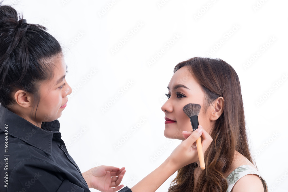 Makeup artist is makeup a asian woman model on white background,applying lipgloss,thailand people Makeup artist is makeup a asian woman model on white background,applying lipgloss,thailand people