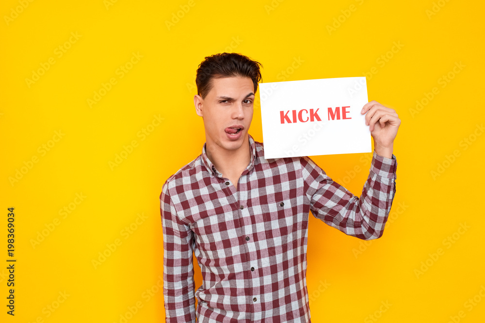 Man tongue out holding table with an inscription kick me Man tongue out holding table with an inscription kick me