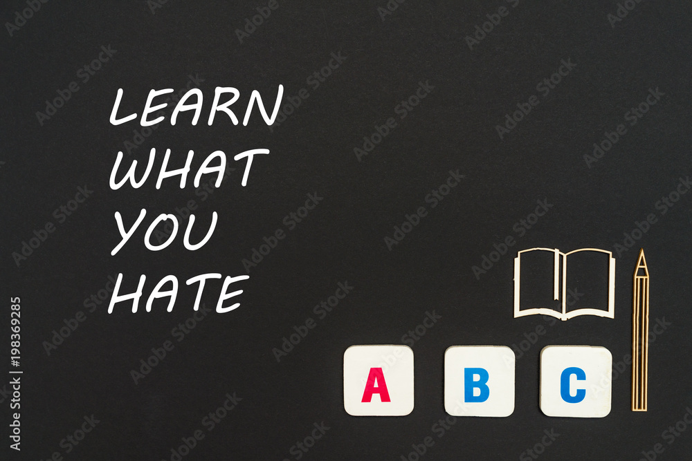 ABC letters and chipboard miniature on blackboard with text learn what you hate ABC letters and chipboard miniature on blackboard with text learn what you hate