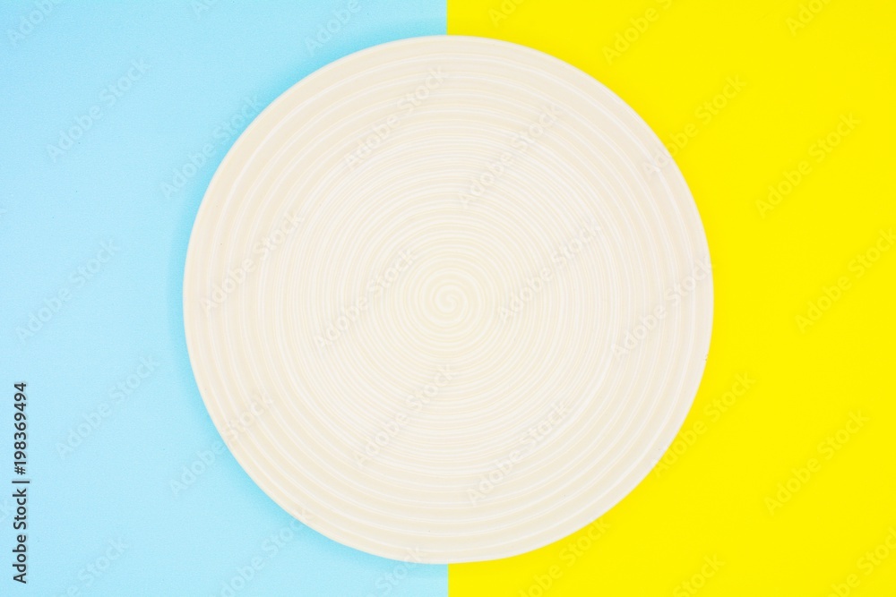 white ceramic dish on blue and yellow paper - background white ceramic dish on blue and yellow paper - background