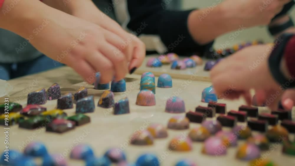 Set of colorful luxury handmade bonbons on white table. Exclusive handcrafted chocolate candy. Homemade dessert preparing by woman. Female hands sorting candies Set of colorful luxury handmade bonbons on white table. Exclusive handcrafted chocolate candy. Homemade dessert preparing by woman. Female hands sorting candies