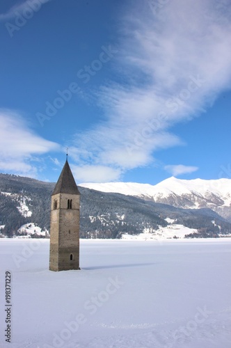 Winter landscape with the famous sunken clock tower in Reschensee (Resia lake) on the border between the South Tyrol (Italian Alps) and Austria.