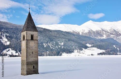 Famous clock tower in iced Resia lake, italian alps, Val Venosta, South Tyrol