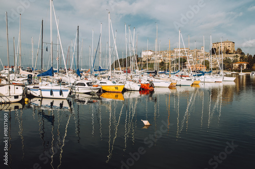 Fotografi Mirror image of the boats in a marina in italy