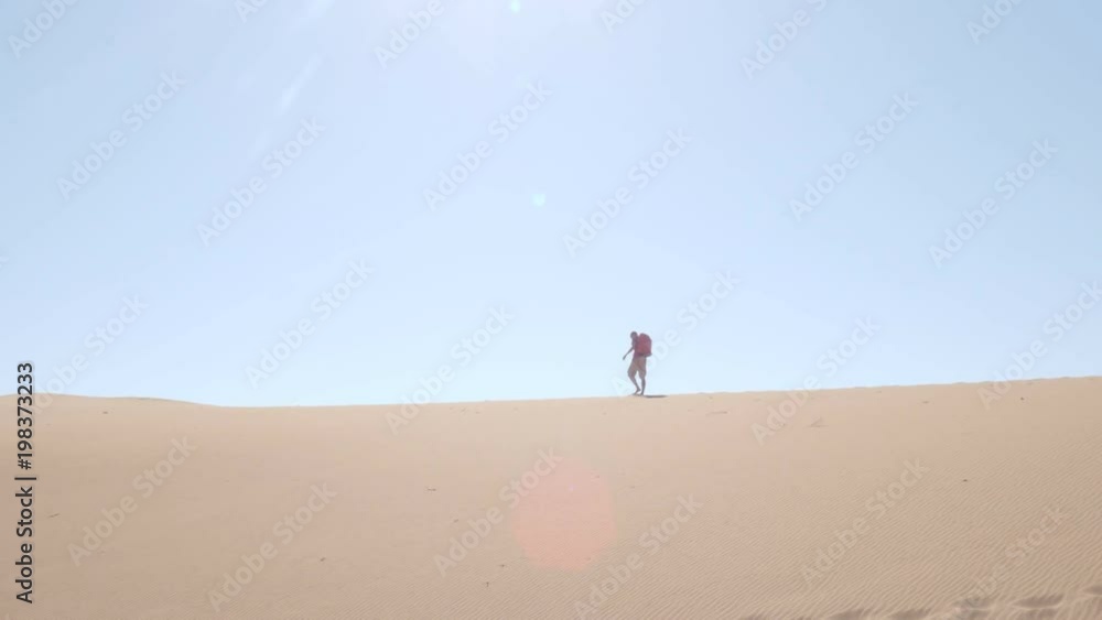 Man backpacking across desert dune in Namibia Africa Man backpacking across desert dune in Namibia Africa