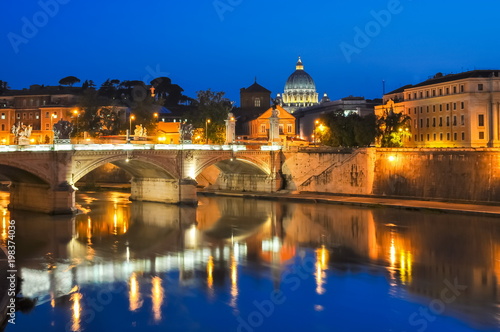 Victor Emmanuel bridge over Tiber river with St. Peter's Cathedral as background at night, Rome, Italy