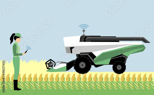A woman farmer controls an autonomous combine harvester. Internet of things in agriculture