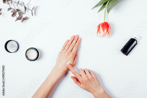 Woman s hands apply cream on skin to test it. Top view.