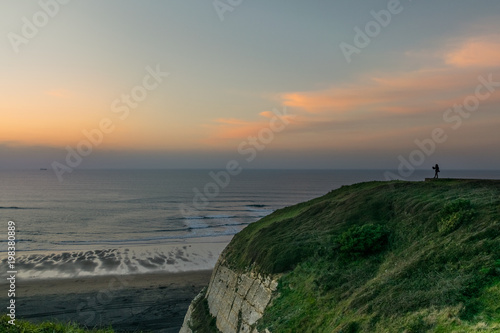 woman looking at the horizon from a cliff at sunset