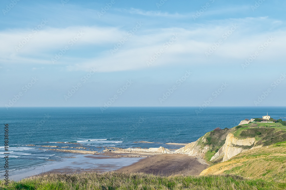 sharp edge elongated rocks with a church in the cliff with the sea on the horizon. sharp edge elongated rocks with a church in the cliff with the sea on the horizon.