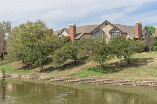 Riverside home, apartment with green oak trees in Irving, Texas, USA. Ducks swimming on canal.