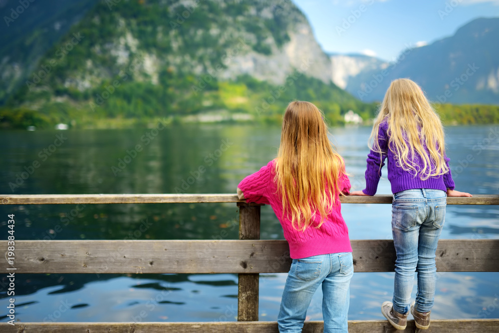 Two girls enjoying the scenic view of Hallstatt lakeside town in the Austrian Alps in beautiful evening light on beautiful day in autumn Two girls enjoying the scenic view of Hallstatt lakeside town in the Austrian Alps in beautiful evening light on beautiful day in autumn