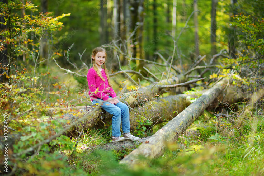 Cute little girl having fun during forest hike on beautiful summer day.