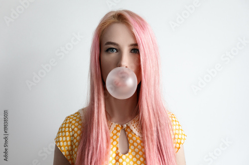 The girl with the pink hair is blowing bubble gum photo