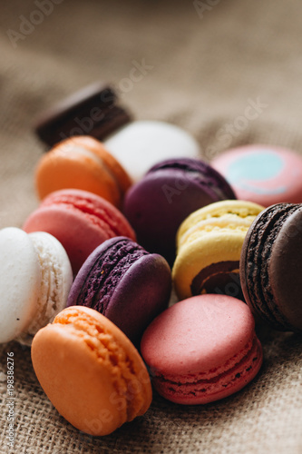 Composition of delicious colorful macaroons on wooden board, sweet dessert