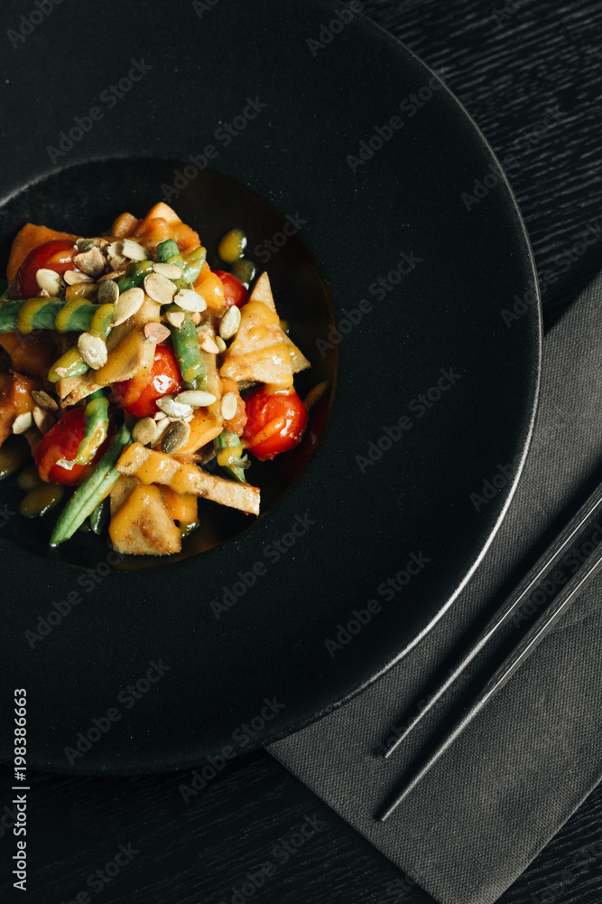 Fresh healthy dinner with seeds and vegetables on black plate Fresh healthy dinner with seeds and vegetables on black plate