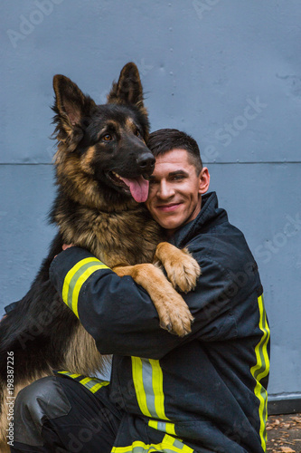 фотографія firefighter plays with a sheepdog, hugs, rejoices