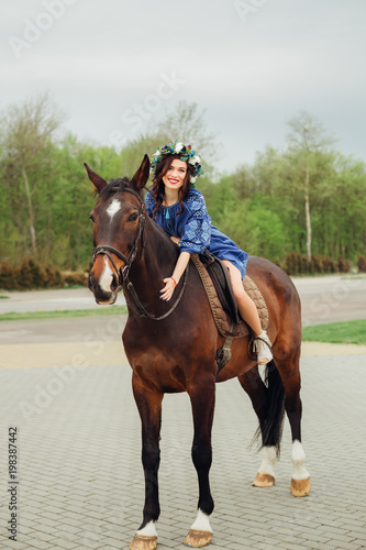 A beautiful girl sits on a horse and looks at the camera lens