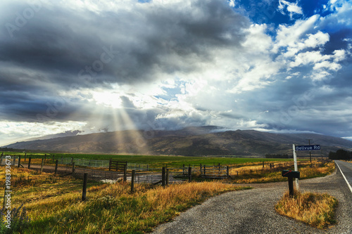 Beautiful countryside scene with sun shining through dark clouds