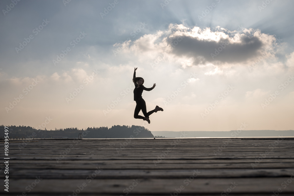 Enthusiastic woman jumping in air against sky