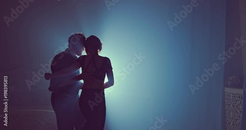 Young couple dance in a dark room with smoke. Slow motion. Silhouette