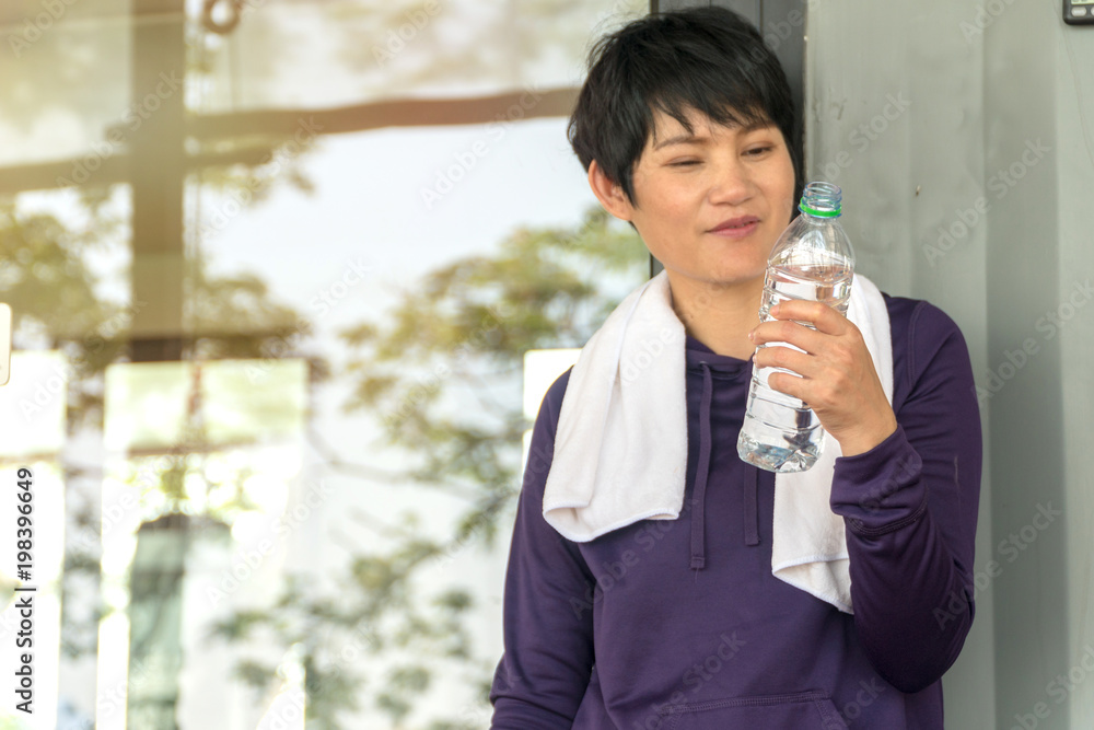 Happy middle-aged woman holding bottle of water after exercise. Sport lifestyle concept. Happy middle-aged woman holding bottle of water after exercise. Sport lifestyle concept.