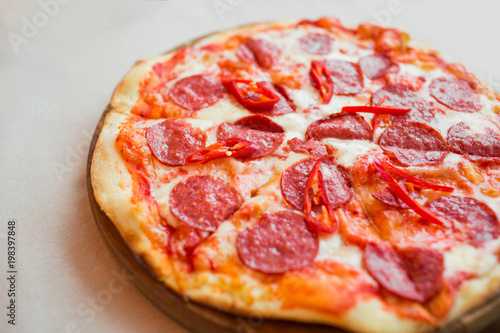 Spicy pizza with cheese and pepperoni. Pepperoni pizza on table.