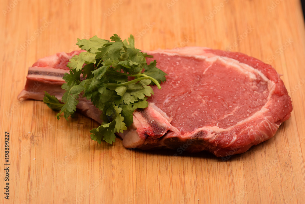 Tenderized steak with salt crystals on wooden cutting board. 