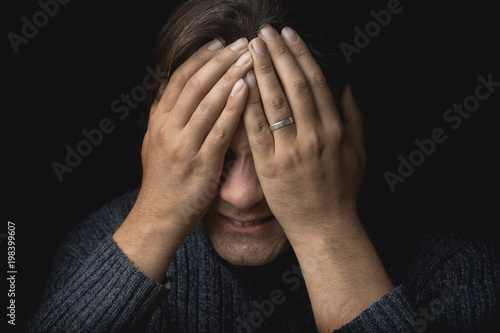 Crying man suffers and covers his face with hands. Depression, mental pain, tragedy, problems in life and grief concept