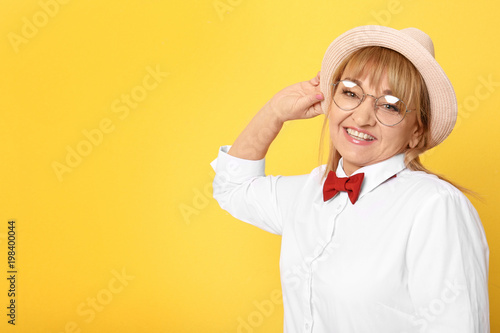 Happy senior woman in hipster outfit on color background