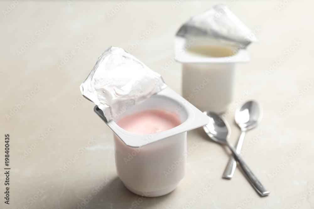Plastic cups with different yogurts on light background Plastic cups with different yogurts on light background
