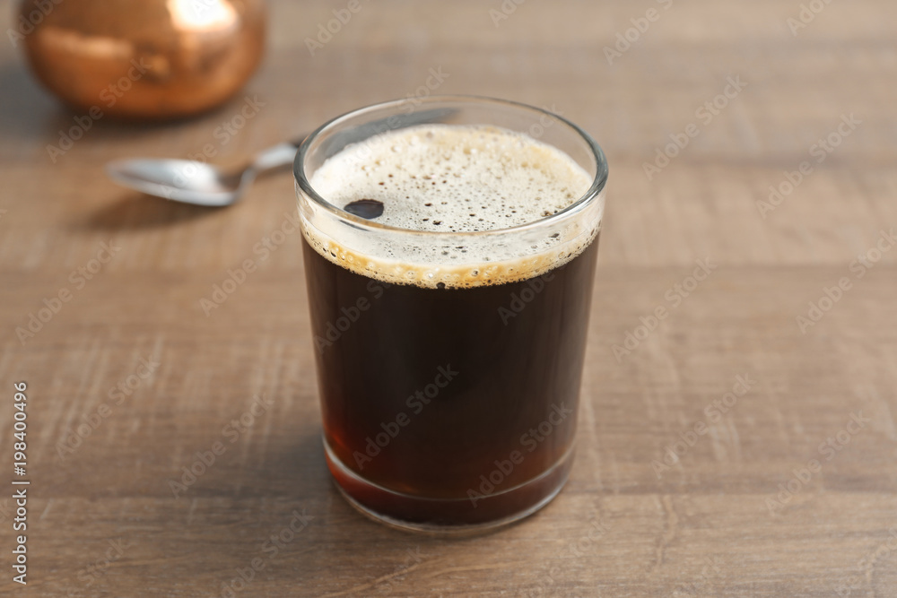 Glass of aromatic hot coffee on wooden table Glass of aromatic hot coffee on wooden table
